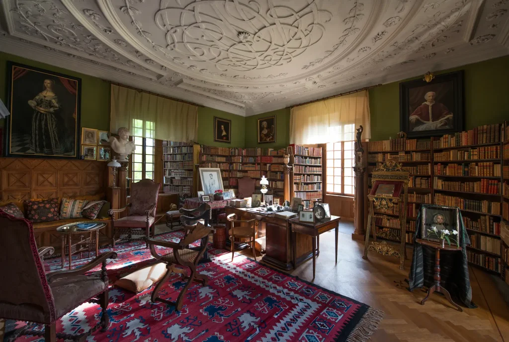 A room with silk furniture, round tables and a large chandelier on the ceiling.